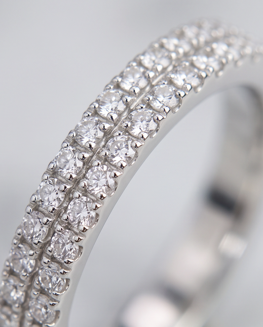 A close up picture of a silver band ring for woman featuring two layers of diamonds and cubic zirconia stones.