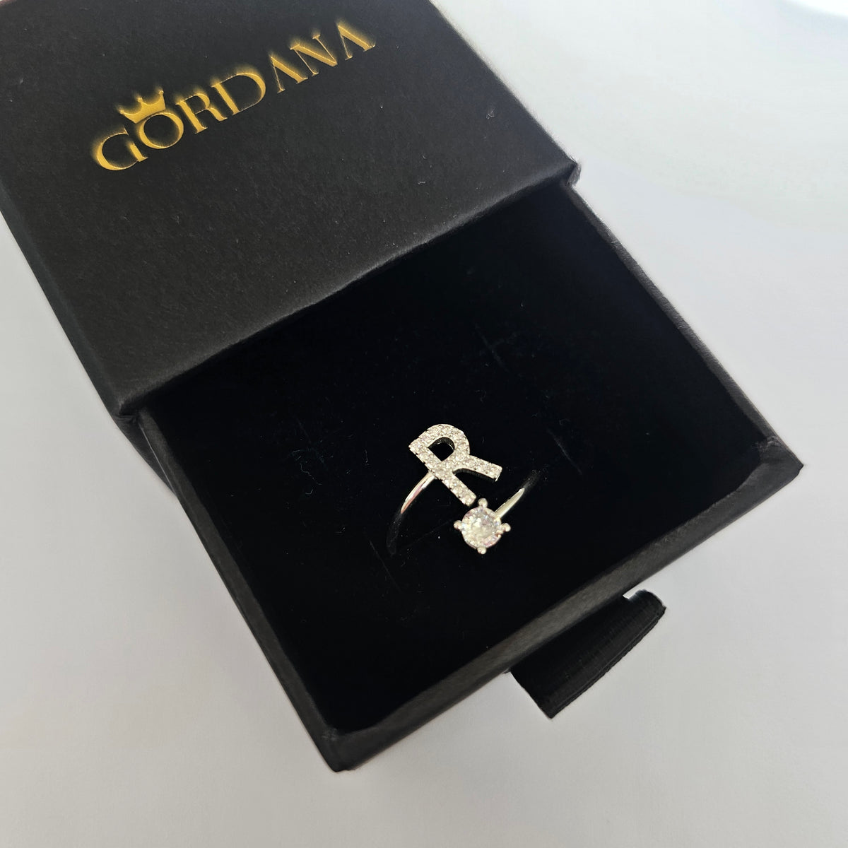 Silver jewelry alphabet ring "R" in black gift box.