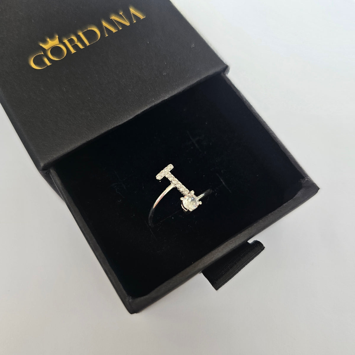 Silver alphabet letter T ring with small gemstones.