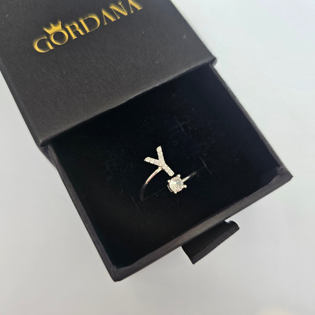 Silver letter Y ring with clear gemstone in black Gordana box.