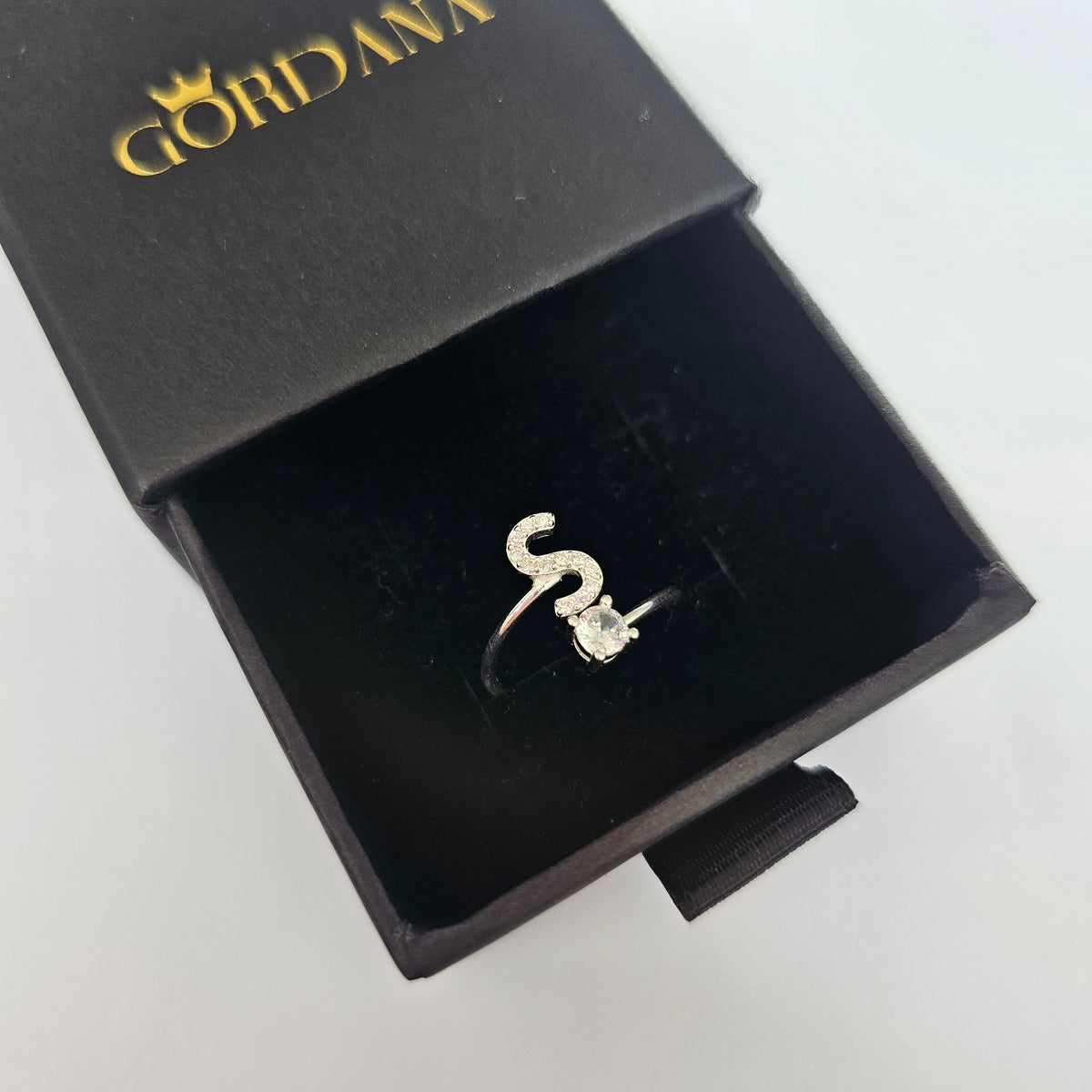 Elegant silver alphabet ring S in black jewelry box.