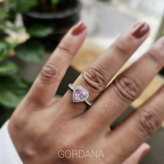 Silver stainless steel heart-shaped ring with a pink gemstone centerpiece on a slender band.