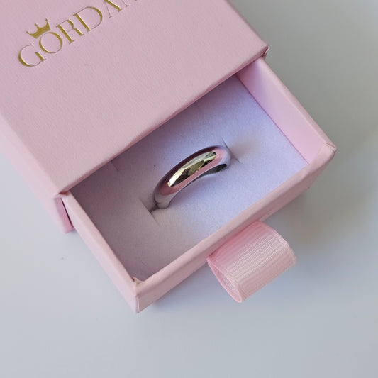 Polished silver stainless steel ring with smooth rounded band in pink jewelry box, unisex fashion jewelry.