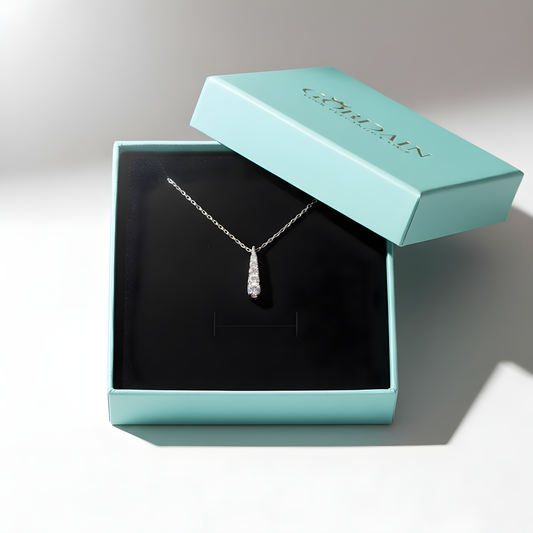 Silver necklace with a pendant in an open light blue jewelry box on a gray background