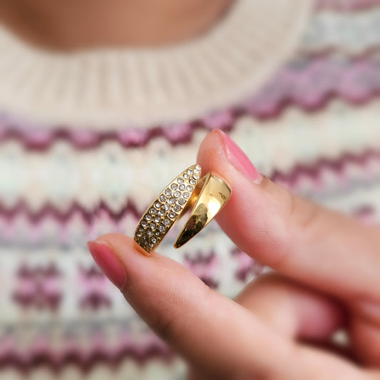 Gold ring with embedded stones held between fingers against a patterned fabric background - Gordana jewelry Mauritius shipping worldwide