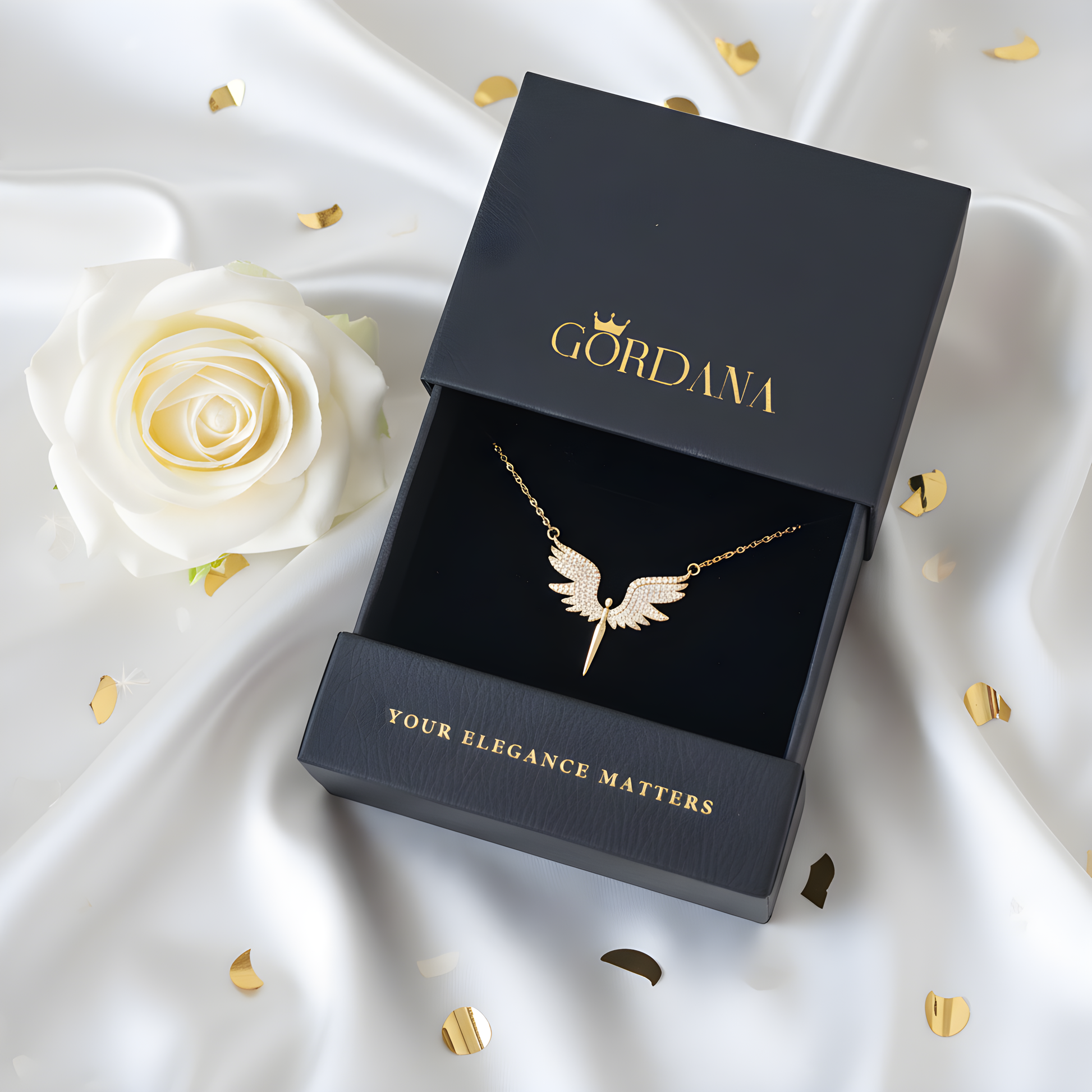 Gold necklace in a black 'Gordana' box on a white fabric background with a white rose.