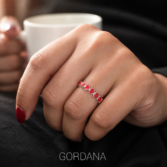 Sterling silver 925 red enamel heart ring worn on hand holding white cup, romantic everyday style