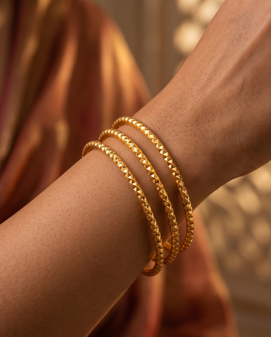 A set of three textured gold bangles for women. 