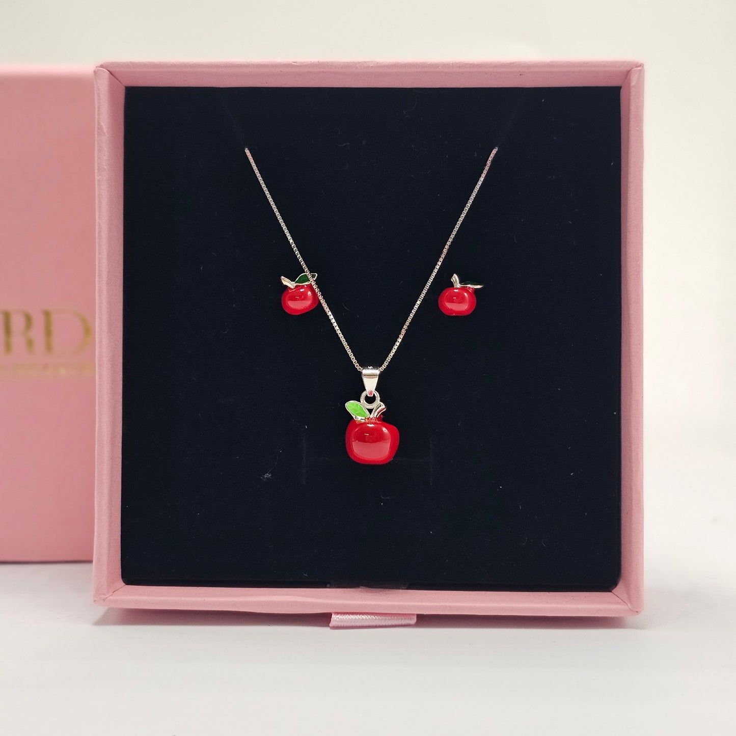 Silver jewelry set featuring stainless steel necklace and earrings with red gemstone apple design, unisex fashion jewelry.