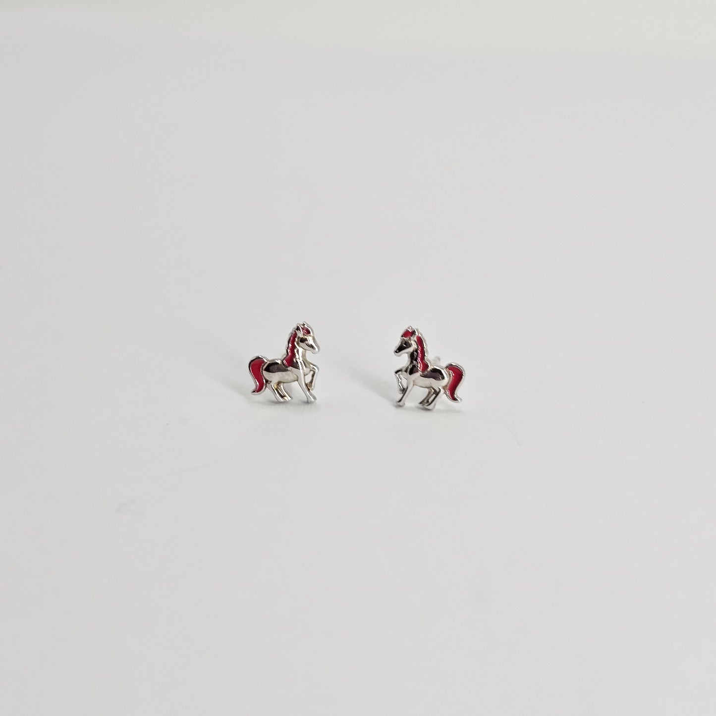 Silver stainless steel horse stud earrings with red accents, stylish unisex fashion jewelry.
