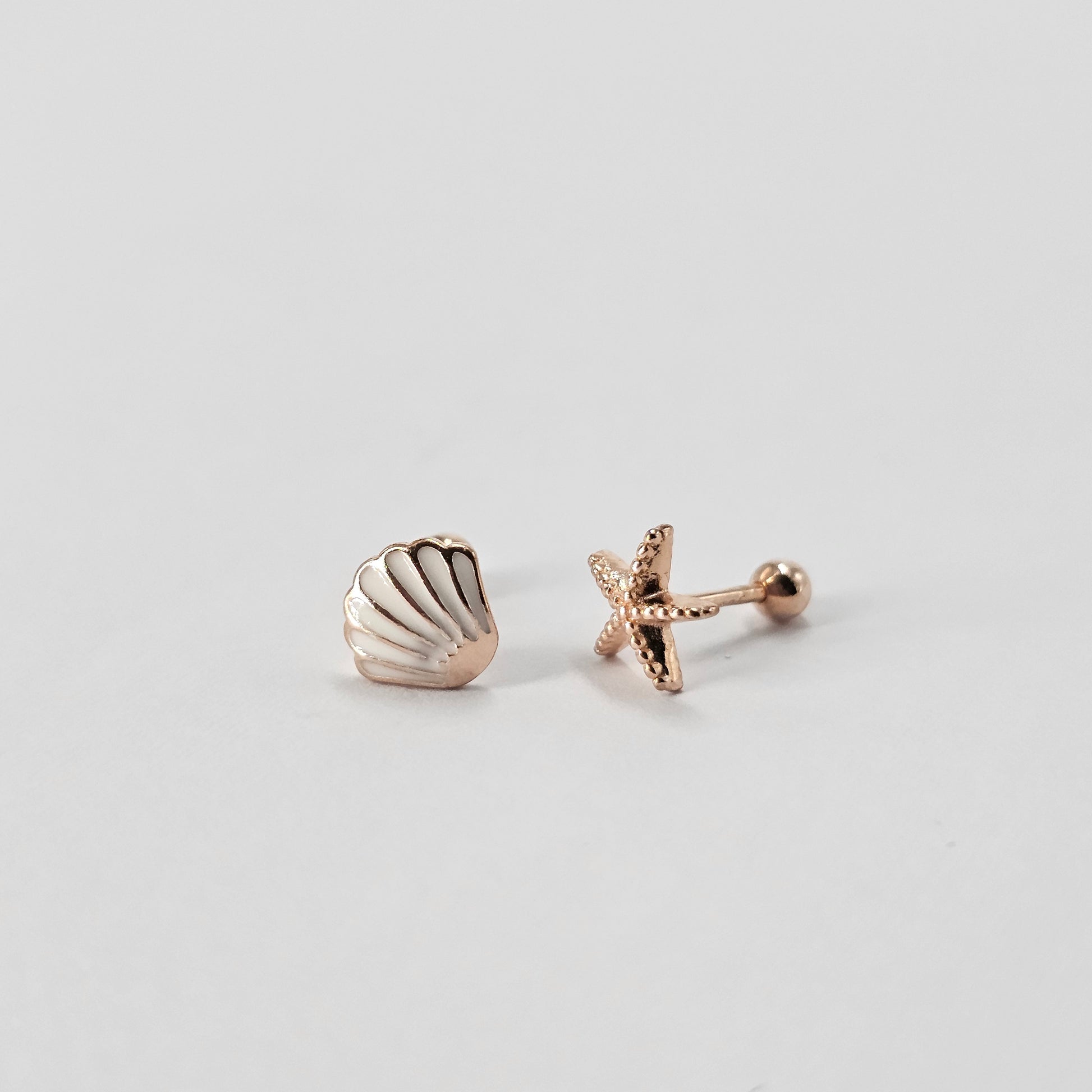 Rose gold shell and starfish-shaped stainless steel earrings with stylish texture, unisex fashion jewelry.