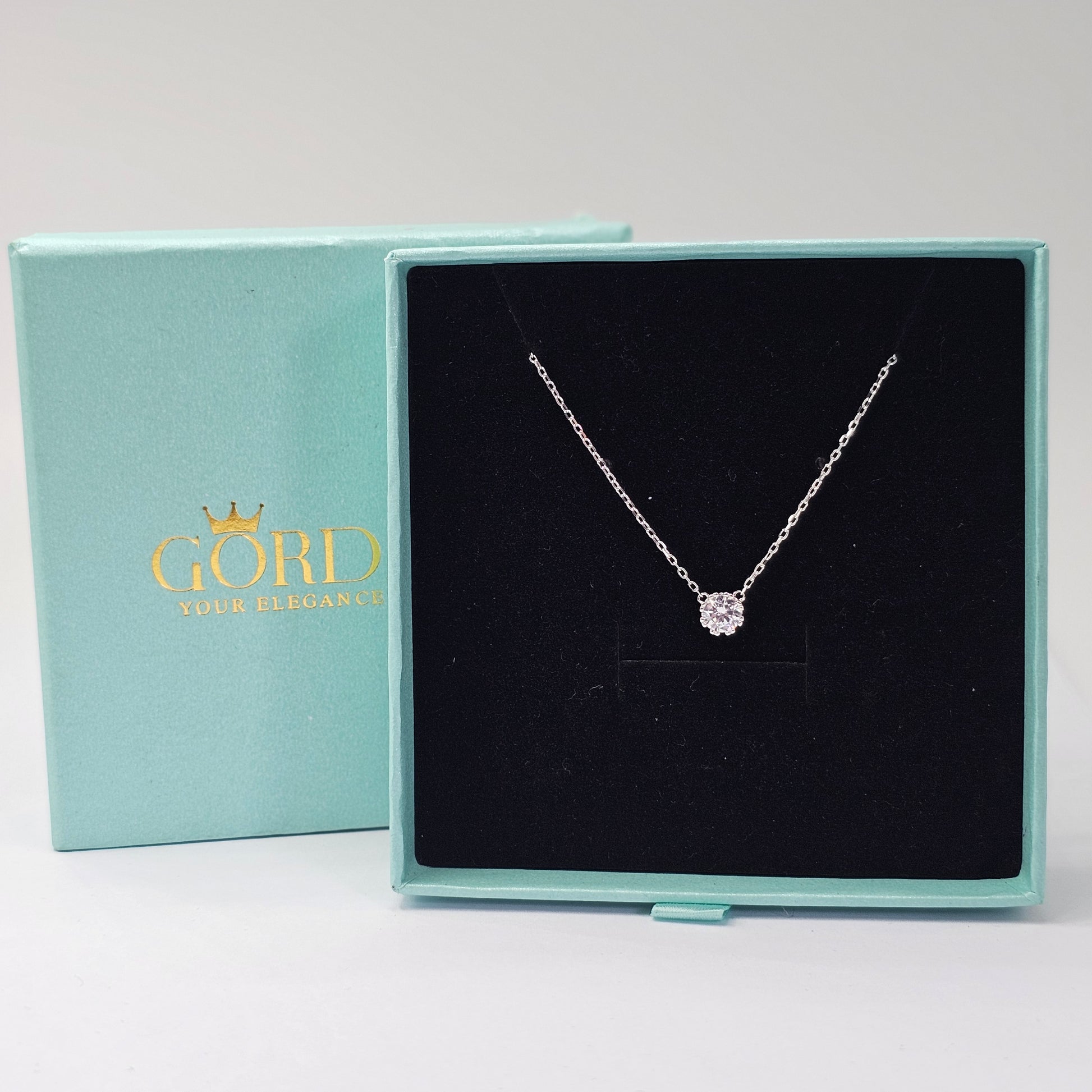 Elegant silver necklace with a delicate gemstone pendant in a black velvet box, showcasing stainless steel jewelry and.