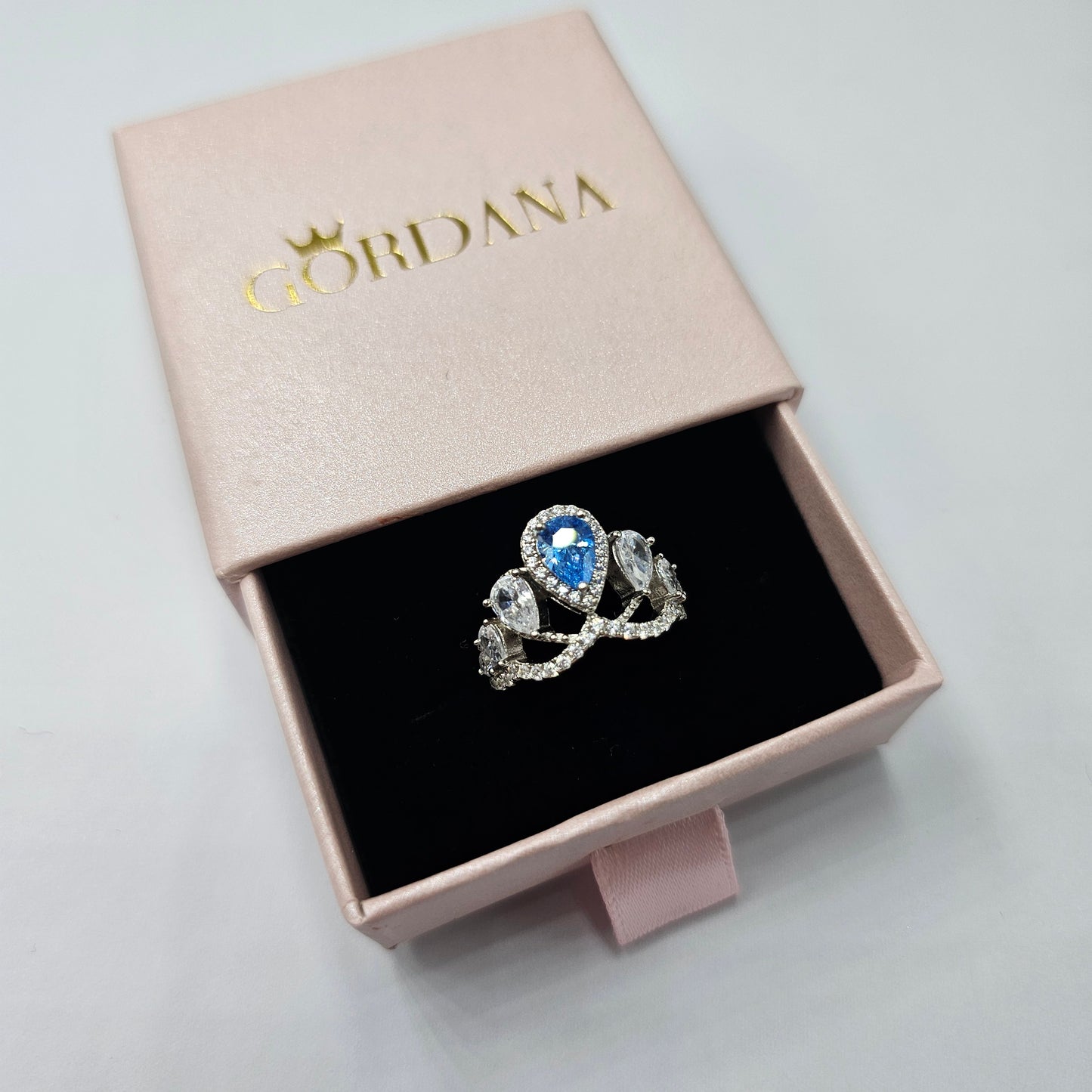 Silver jewelry ring with blue gemstone and intricate stainless steel design in pink gift box, unisex fashion jewelry.