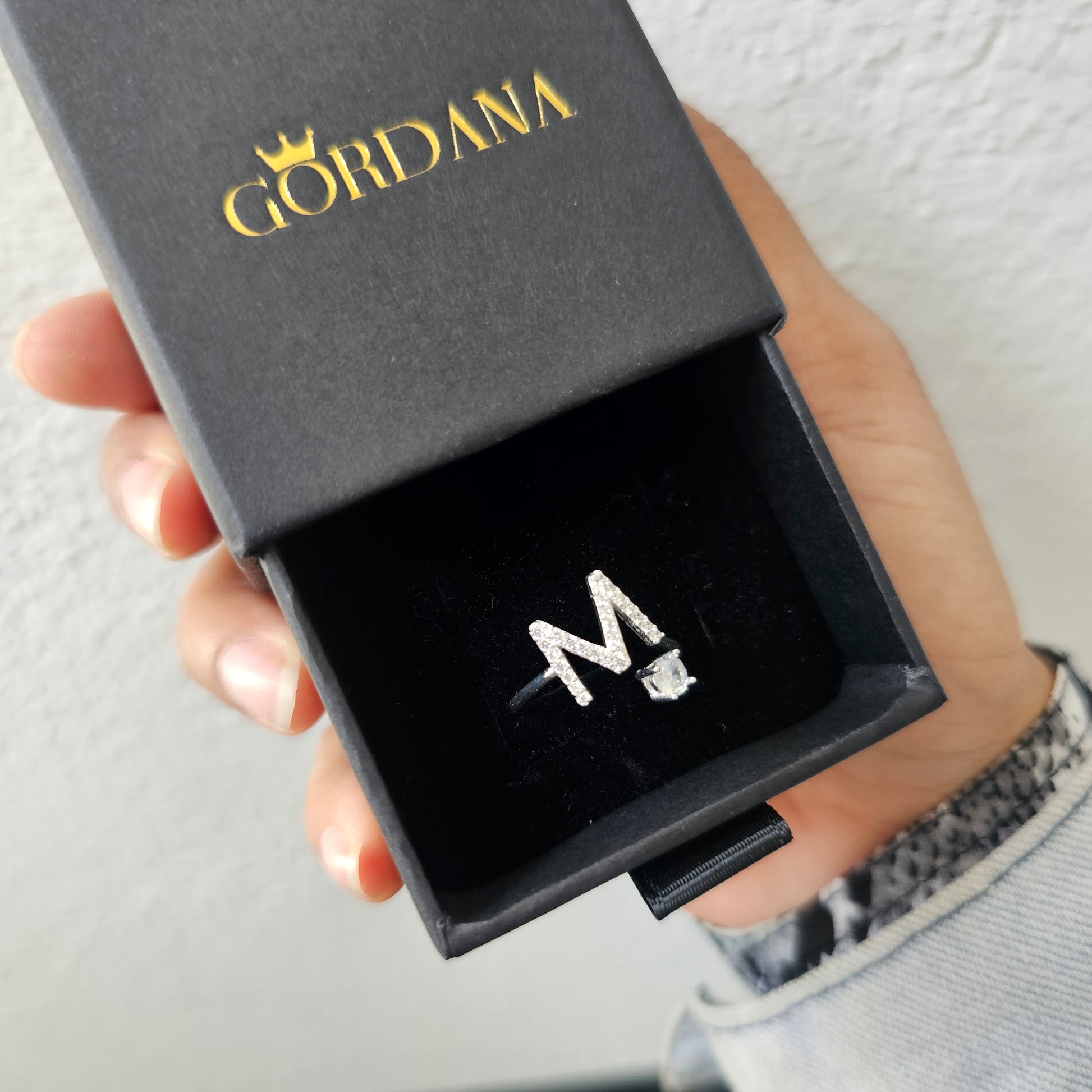 Silver jewelry stainless steel ring with letter M and clear gemstone in black Cordana box.