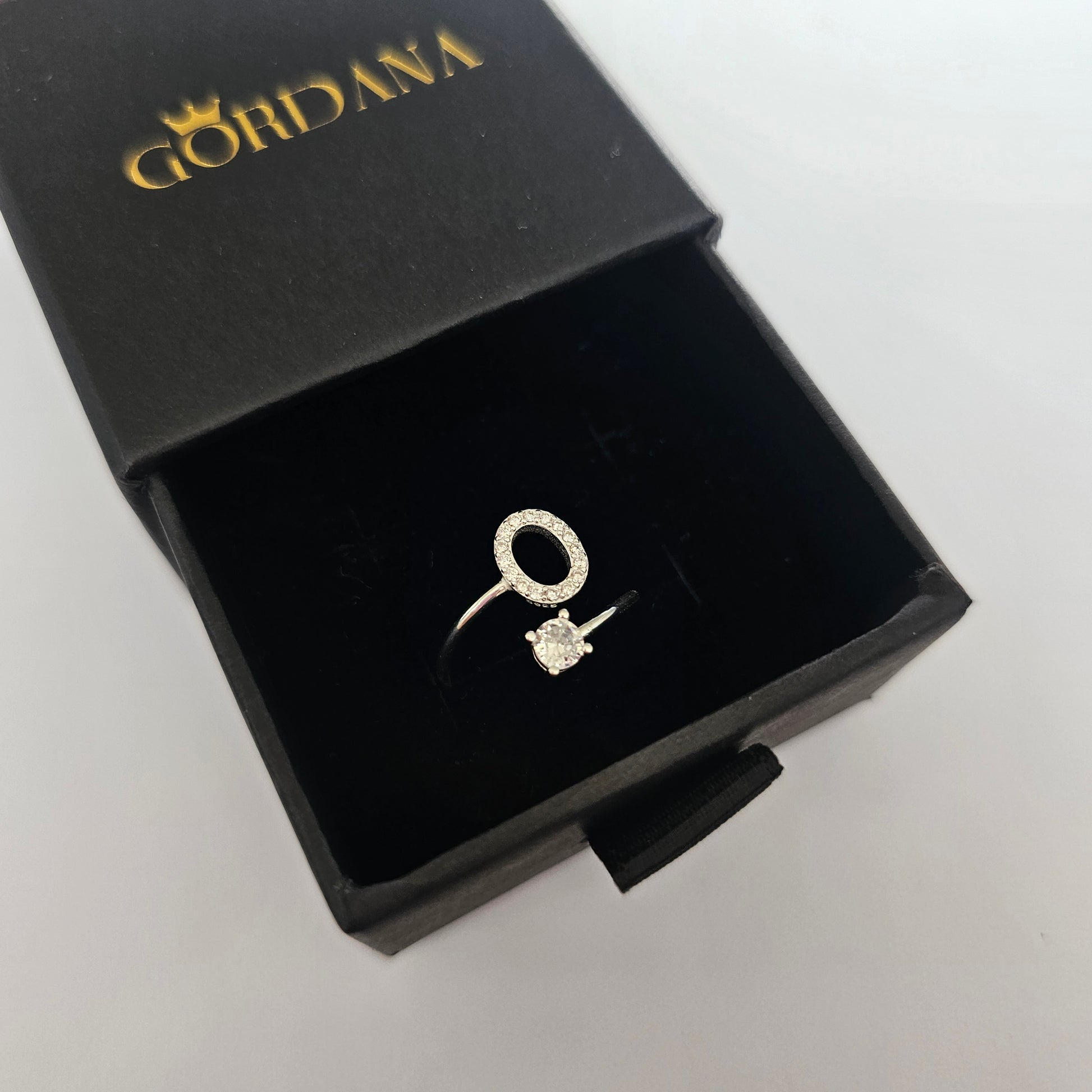 Elegant silver alphabet ring with gemstone accent in black luxury box, stainless steel jewelry.