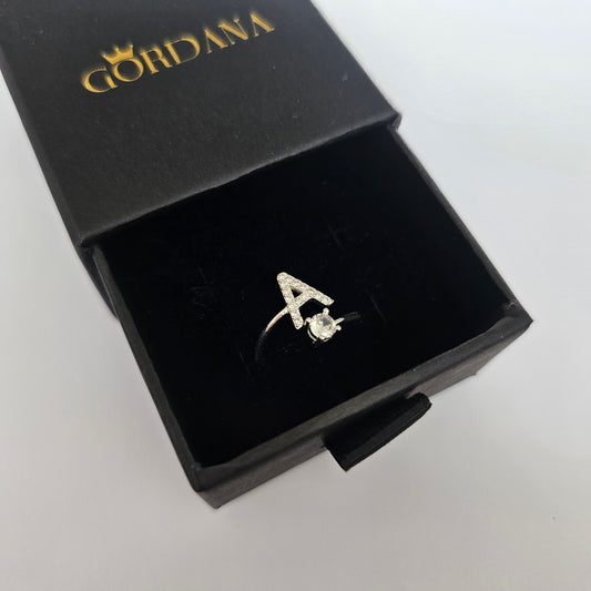 Silver alphabet ring 'A' with a small gemstone, elegant stainless steel jewelry in a black box, unisex fashion jewelry.