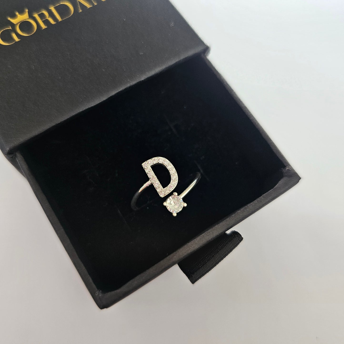Silver stainless steel ring featuring letter D and a small gemstone, elegant unisex fashion jewelry.