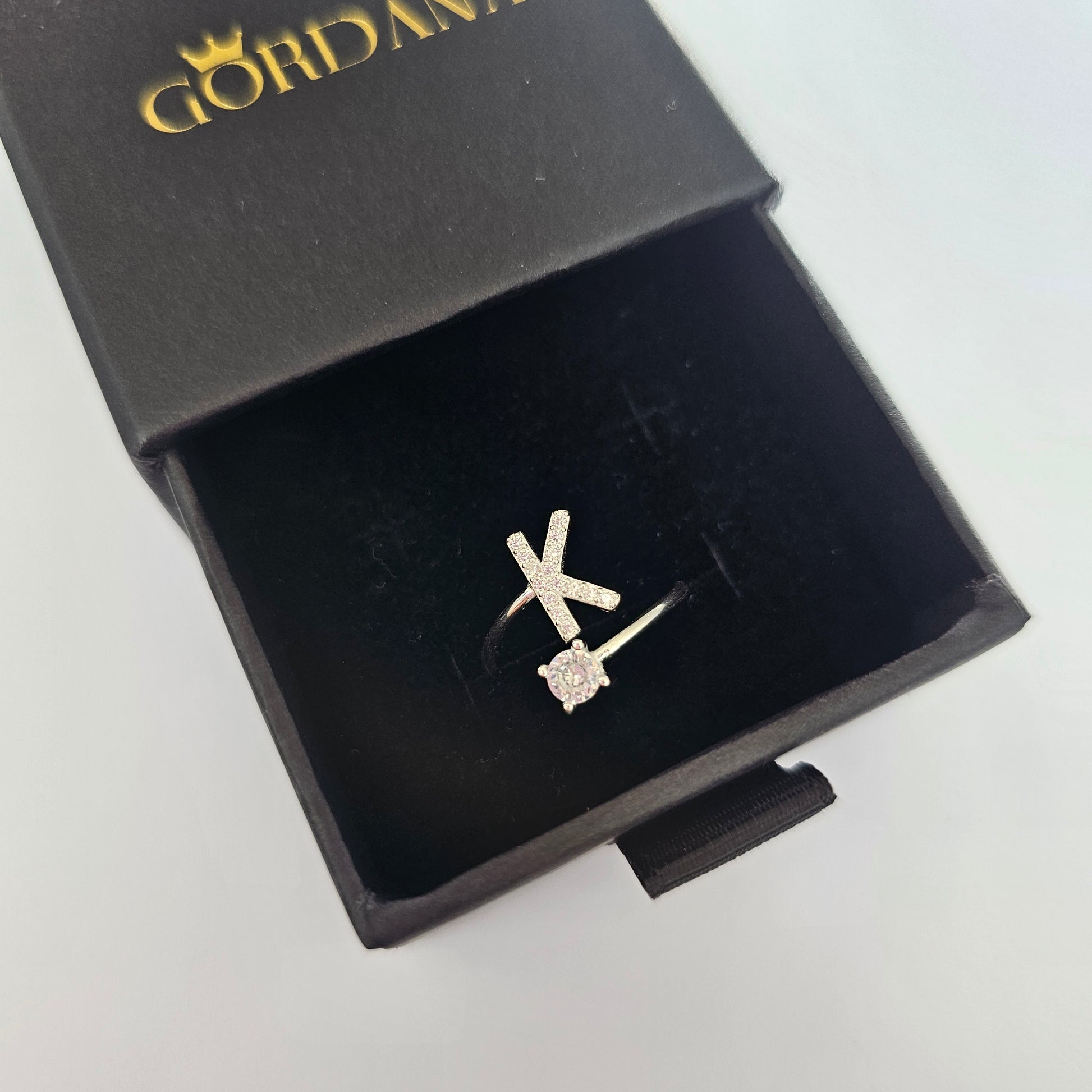 Silver alphabet K ring with gemstone accent in black jewelry box, stainless steel unisex jewelry.