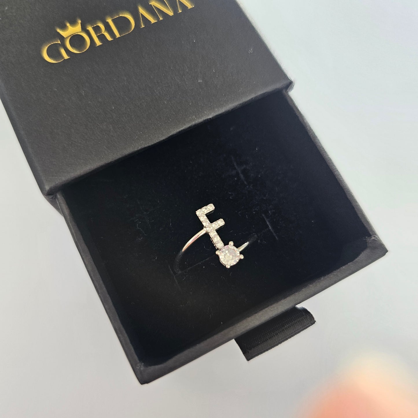 Silver stainless steel letter F ring with gemstone accent in black jewelry box, unisex fashion jewelry.