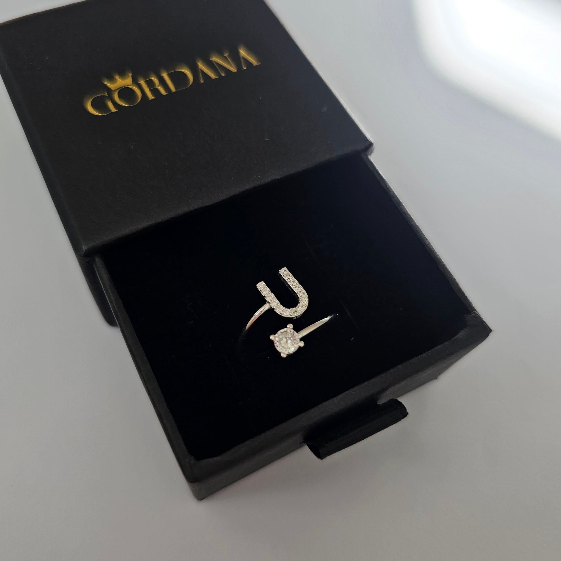 Silver stainless steel letter P ring with a small clear gemstone, elegant unisex fashion jewelry in black luxury box.