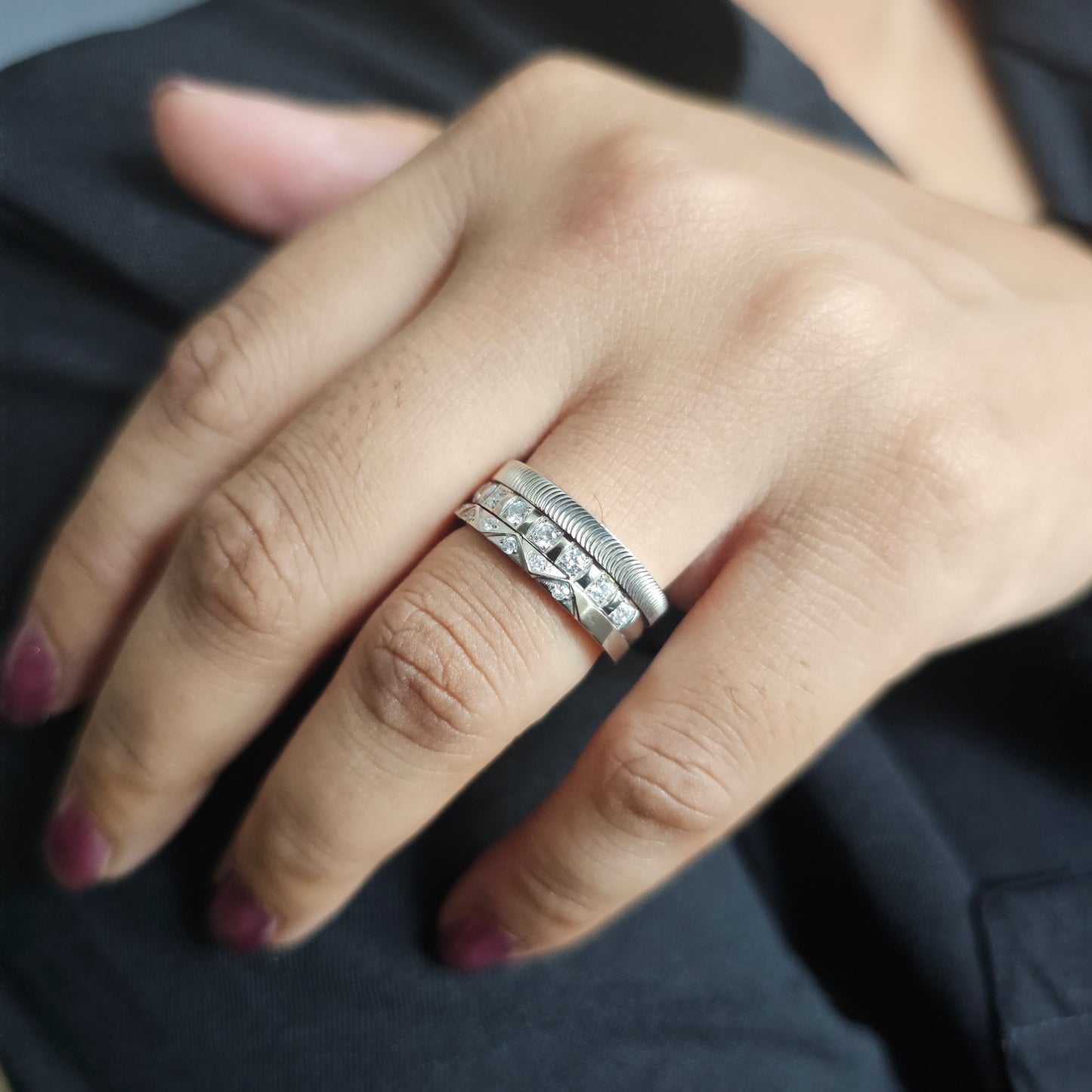 Close-up of a hand wearing three stackable silver plated stainless steel rings designed for women