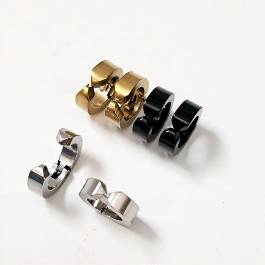 Set of three metallic rings in gold, black, and silver on a white background - Clip-on earrings