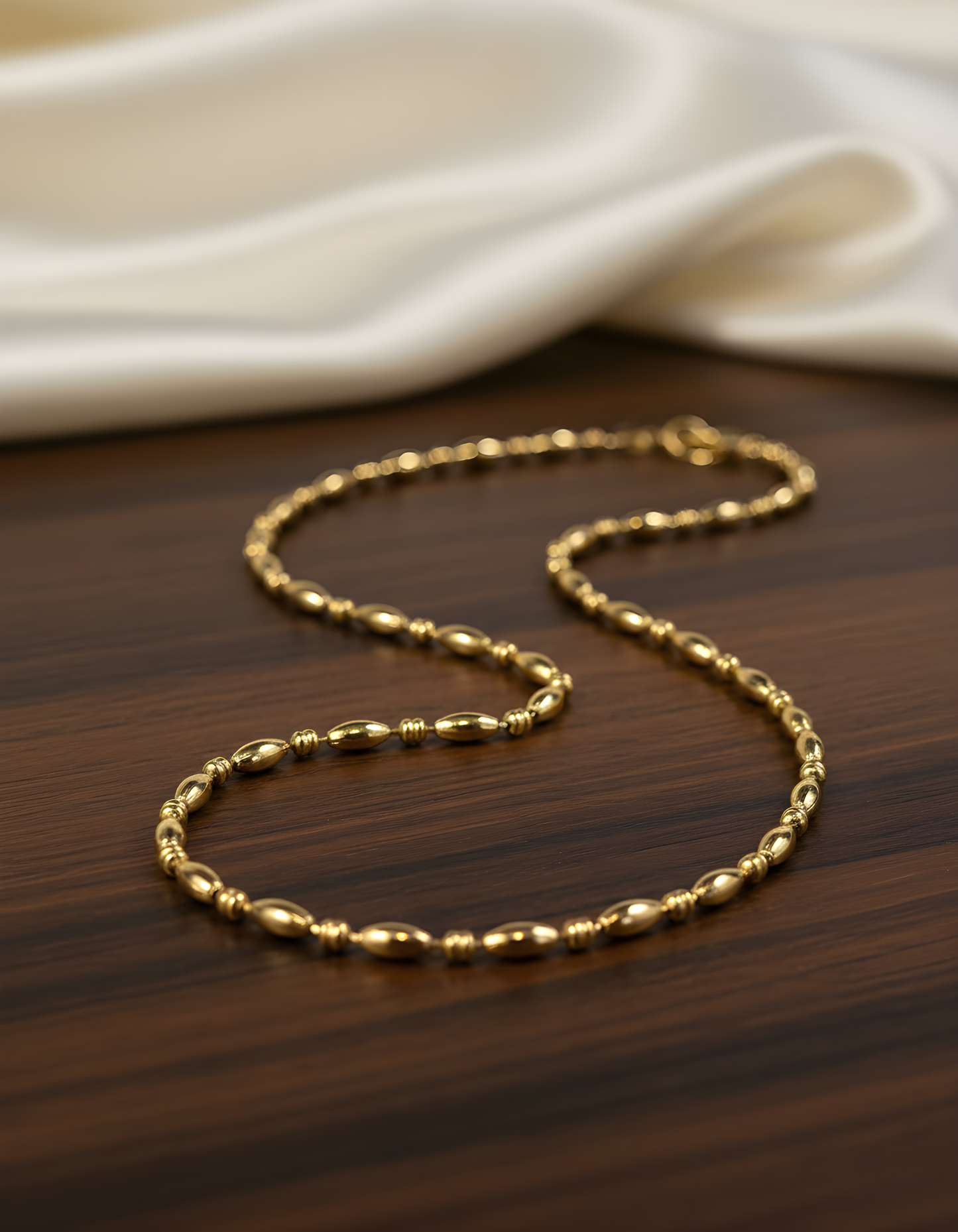 Luxury gold beaded stainless steel necklace for women – elegant minimalist chain necklace on a wooden table. 