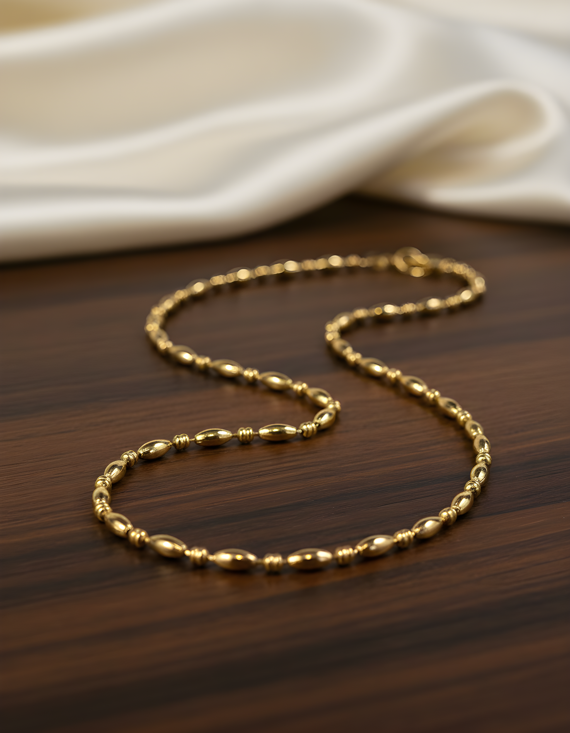Luxury gold beaded stainless steel necklace for women – elegant minimalist chain necklace on a wooden table. 