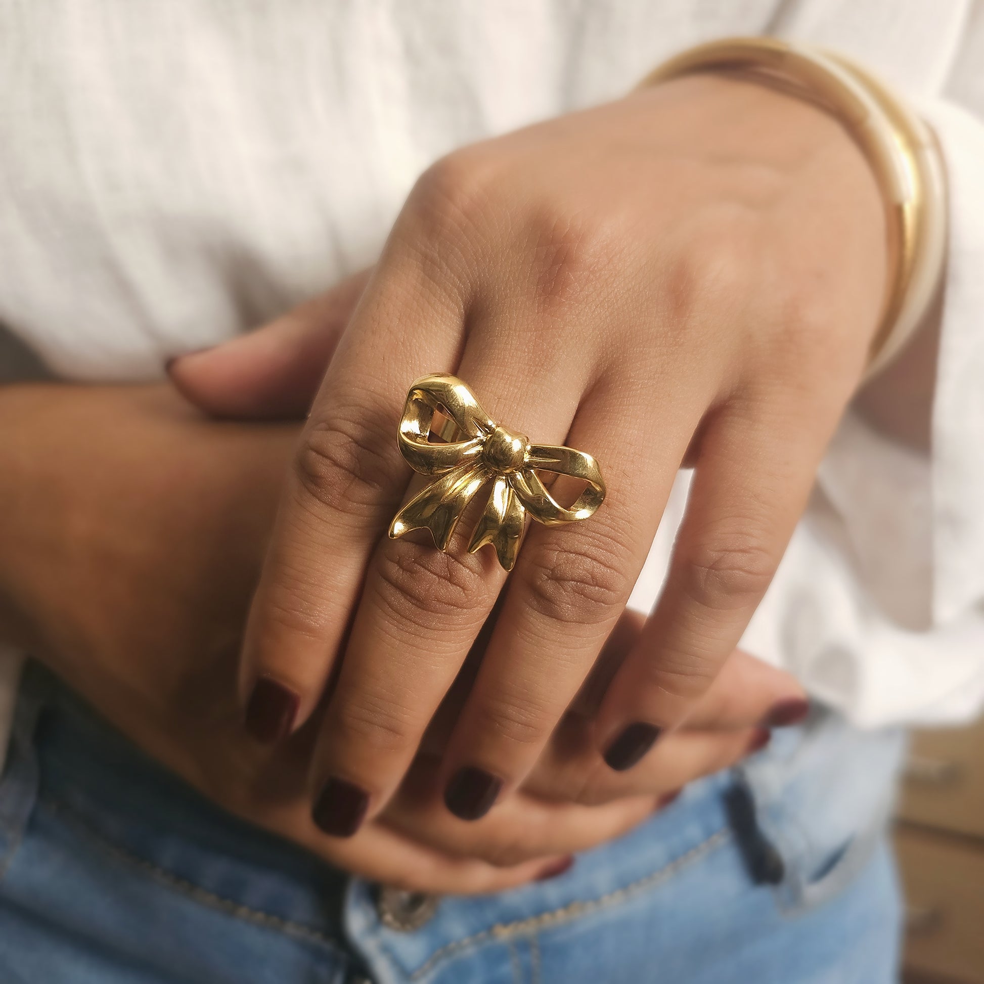 A luxury stainless steel Gold plated bow-shaped ring on a person's finger. A statement ring made for bold ladies. Gordana Jewelry Mauritius. 