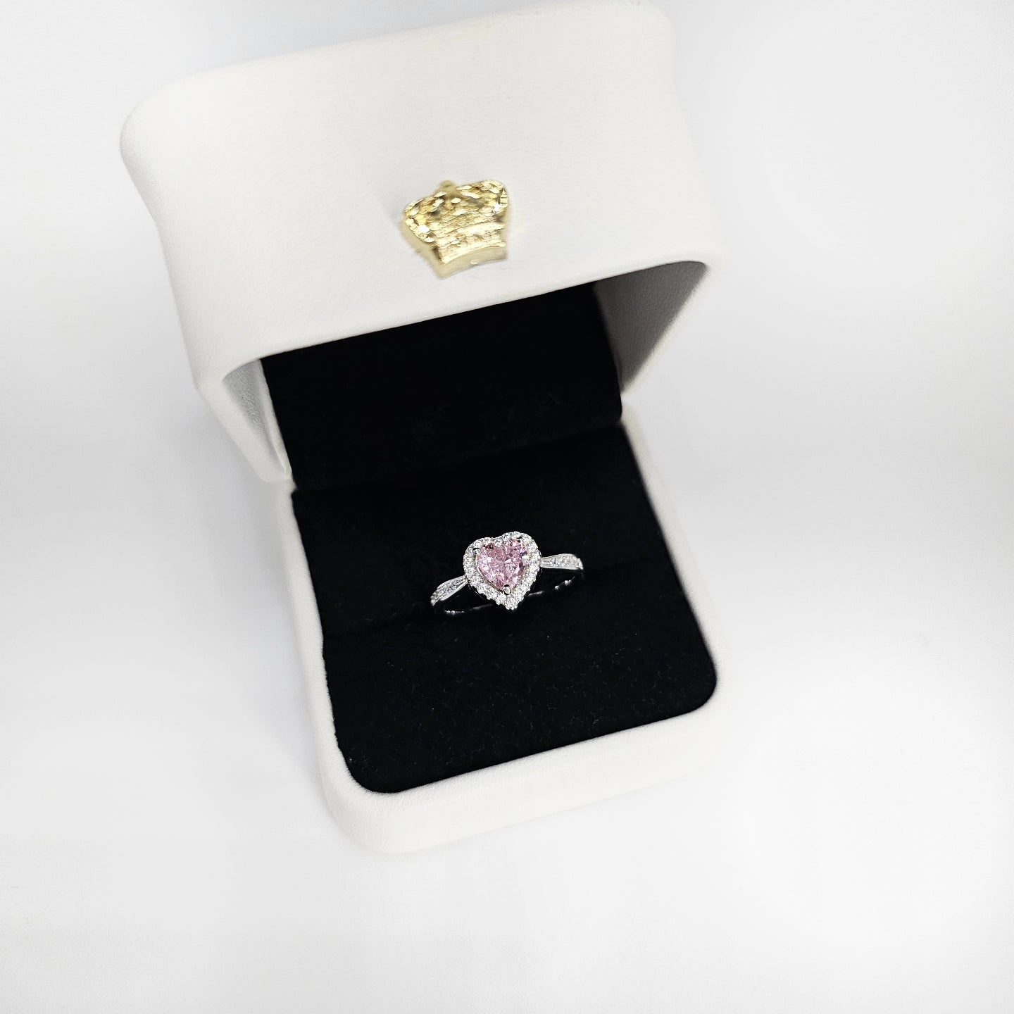 Silver ring with heart-shaped pink gemstone on a thin band in white jewelry box.