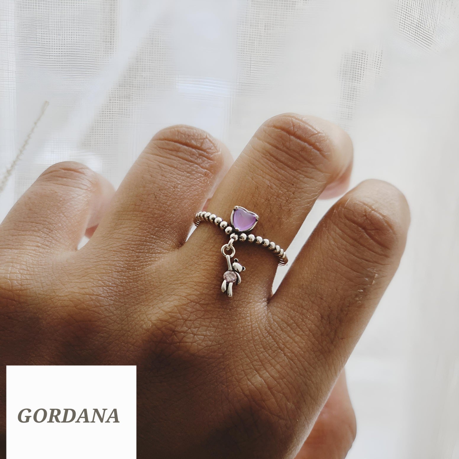 Silver stainless steel teddy ring with purple gemstone and dangling charm, unisex fashion jewelry.