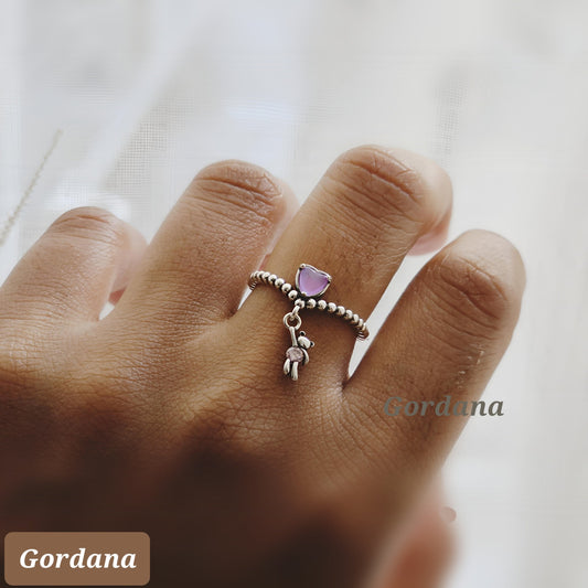 Silver stainless steel teddy ring with pink gemstone charm, elegant unisex fashion jewelry.