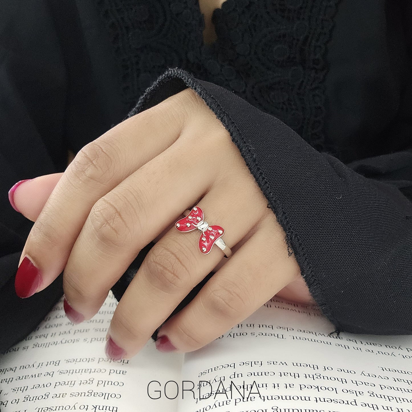 A woman's hand wearing a luxury and cute sterling silver ring with a red bow with silver dots. Gordana Jewelry Mauritius. 