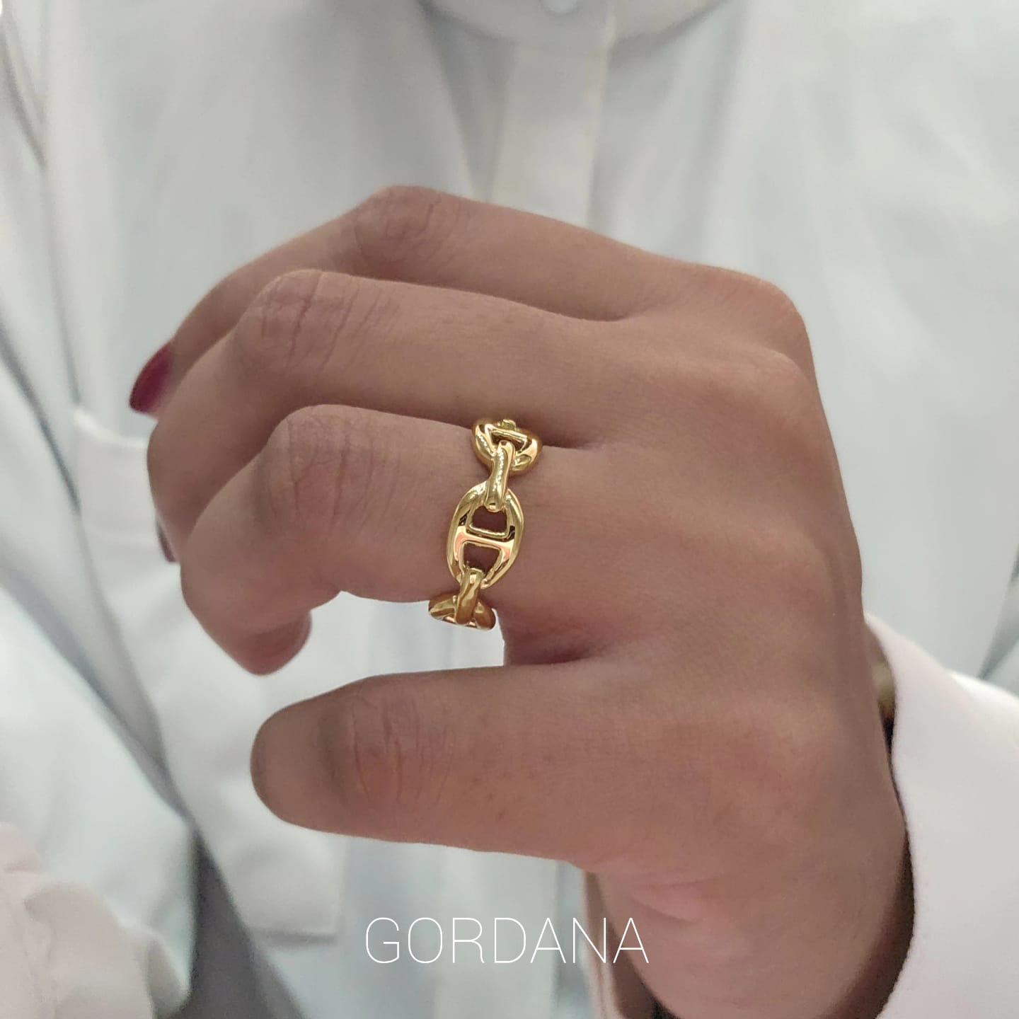 Gold-toned stainless steel chain link ring with a polished finish on a model's finger.