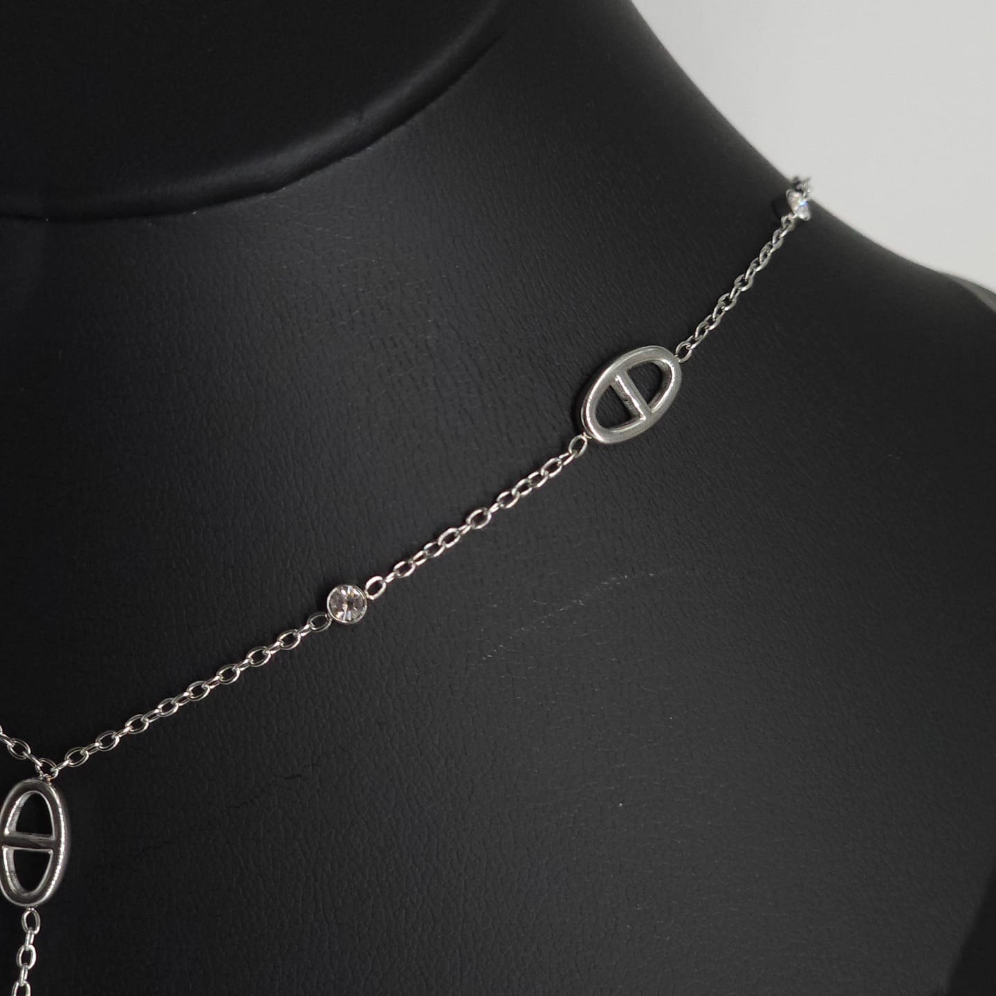 Delicate silver stainless steel necklace with oval-shaped links and subtle chain design on black display bust.