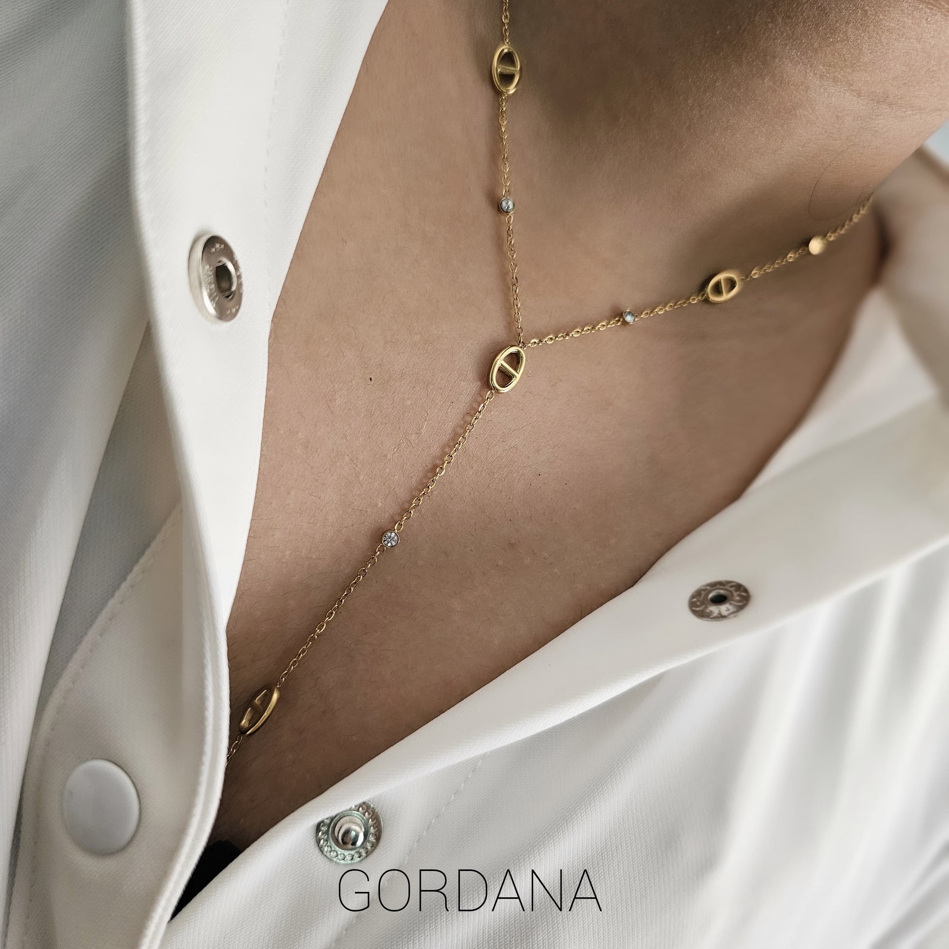 Delicate silver stainless steel necklace with 18k gold-plated geometric charms on layered chain.
