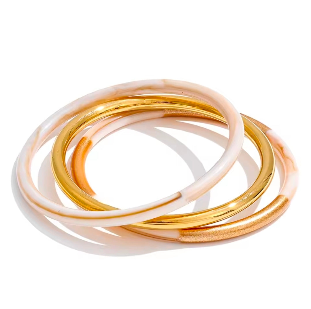 A set of three stackable resin and gold plated stainless steel bangles. 