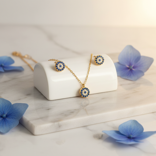 Gold evil eye necklace and earrings set with blue gemstone.