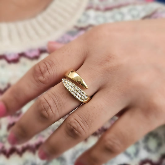 Gold ring with diamond accents on a person's finger against a patterned background