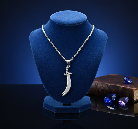Silver necklace with a sword pendant on a blue velvet stand against a dark background.