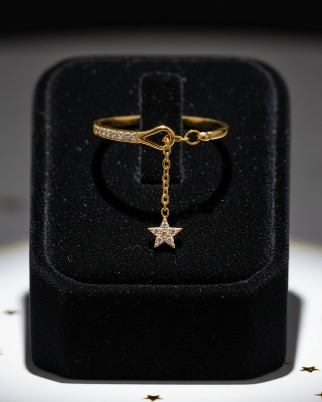 Stainless steel gold ring with a star charm featuring cubic zirconias stones on a black jewelry box