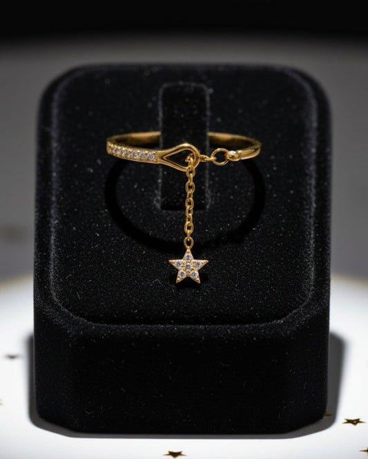 Stainless steel gold ring with a star charm featuring cubic zirconias stones on a black jewelry box