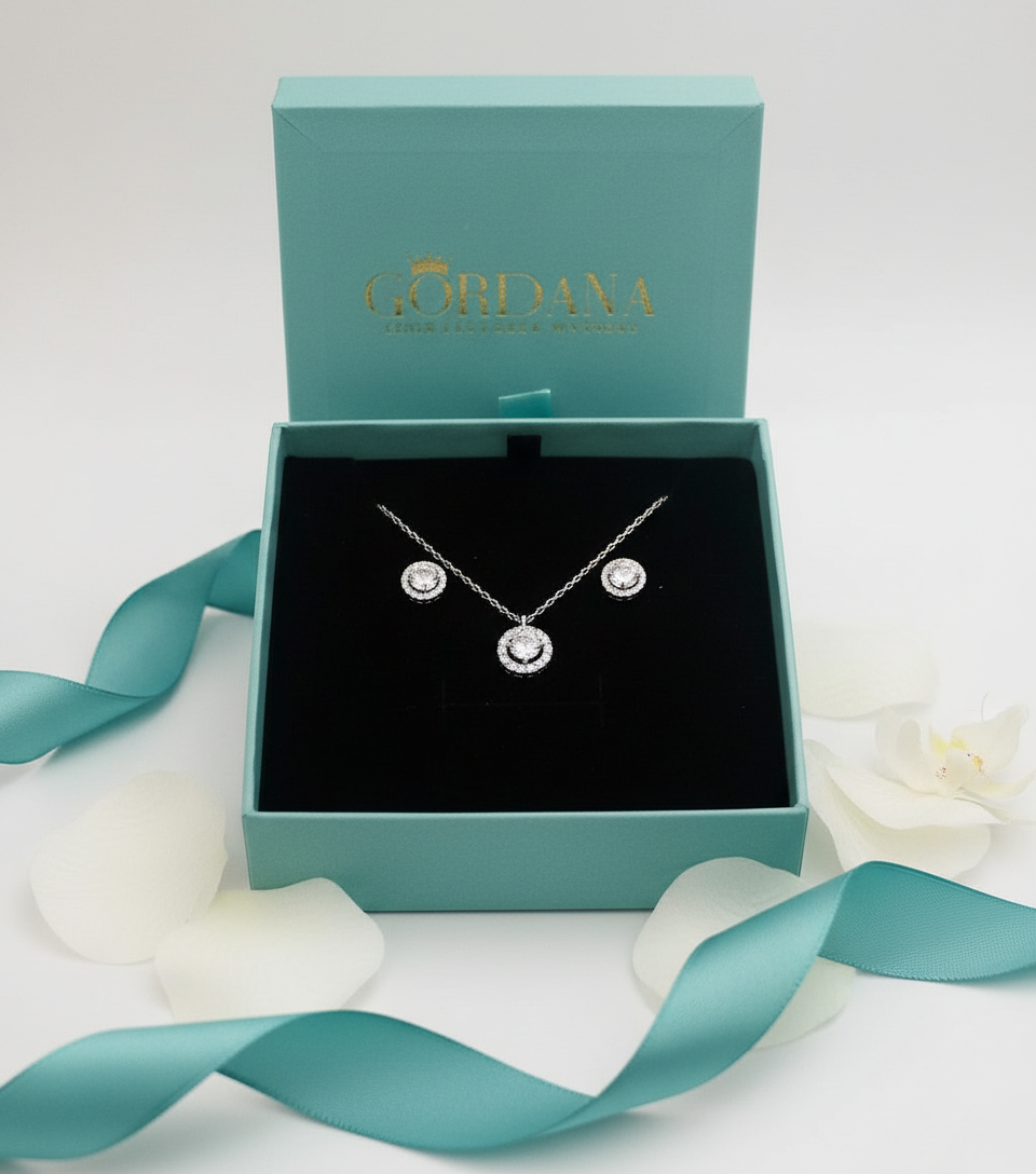 Silver Jewelry set featuring a necklace and a pair of studs in a GORDANA box with a teal ribbon on a white background