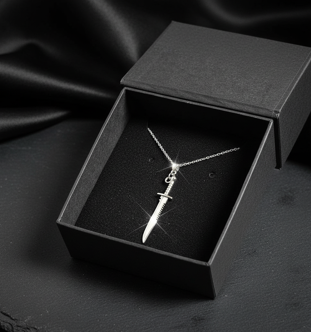 Silver sword-shaped necklace in a black box on a dark fabric background