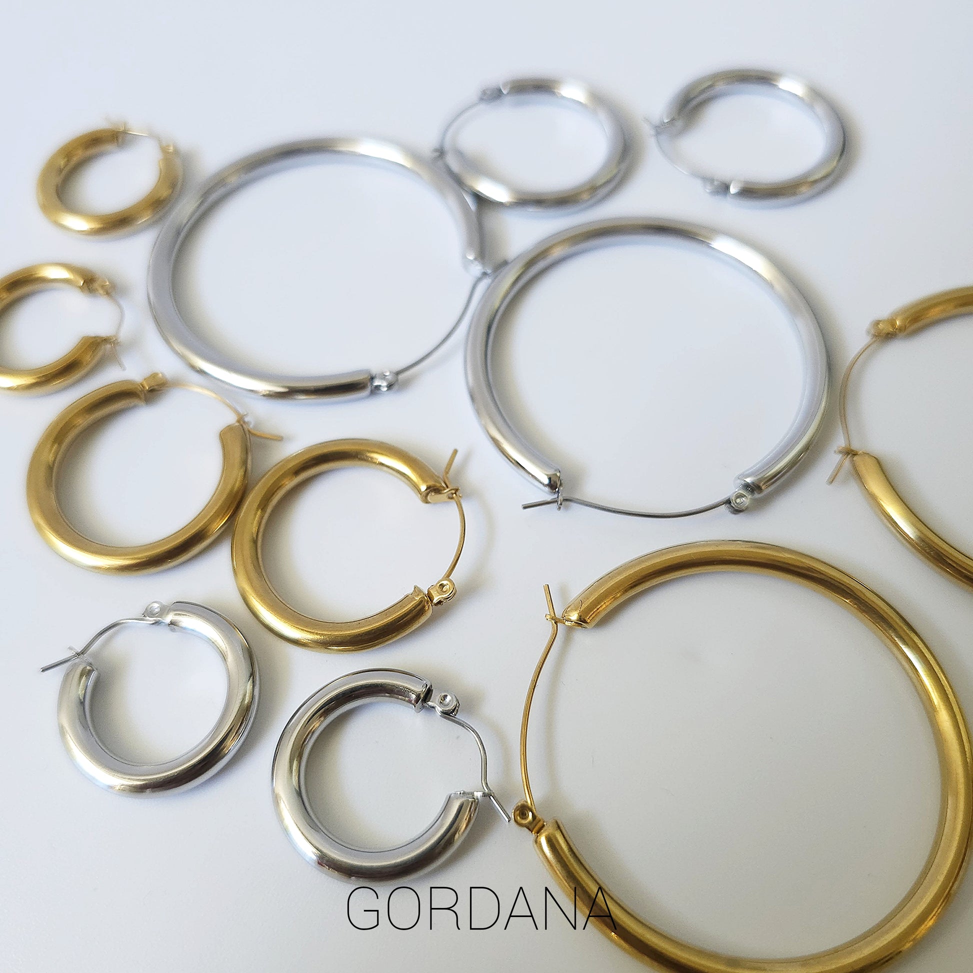 Assorted gold and silver stainless steel hoop earrings in multiple sizes, elegant unisex fashion jewelry.