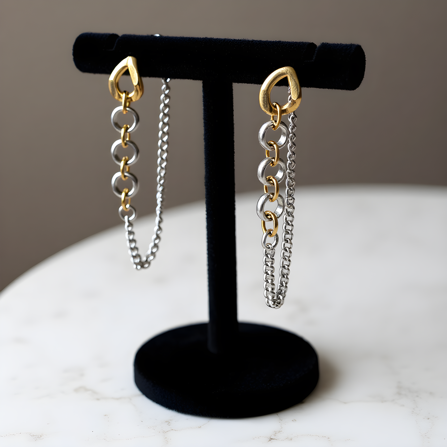 Pair of chain earrings on a black stand with a neutral background