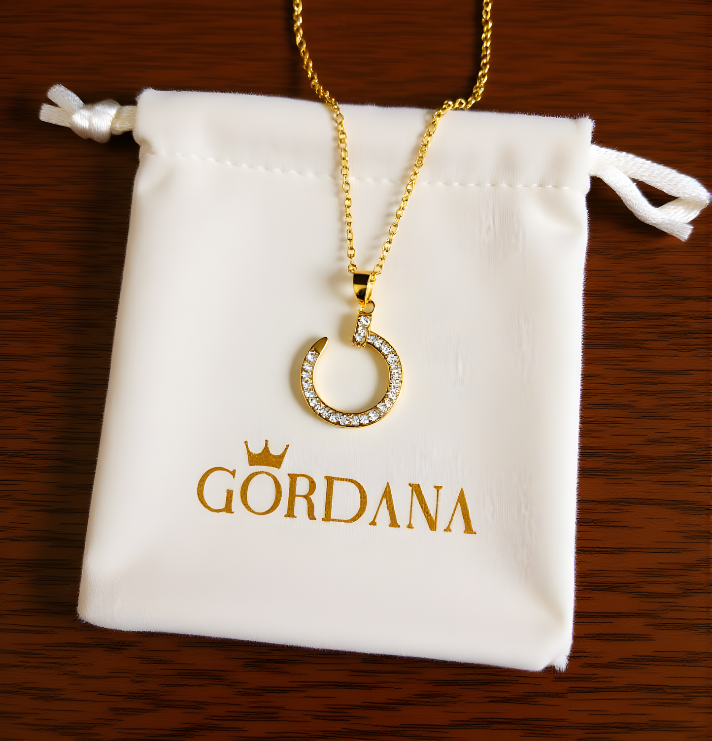 Gold necklace with a pendant on a Gordana branded pouch.