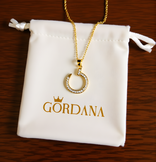 Gold necklace with a pendant on a Gordana branded pouch.