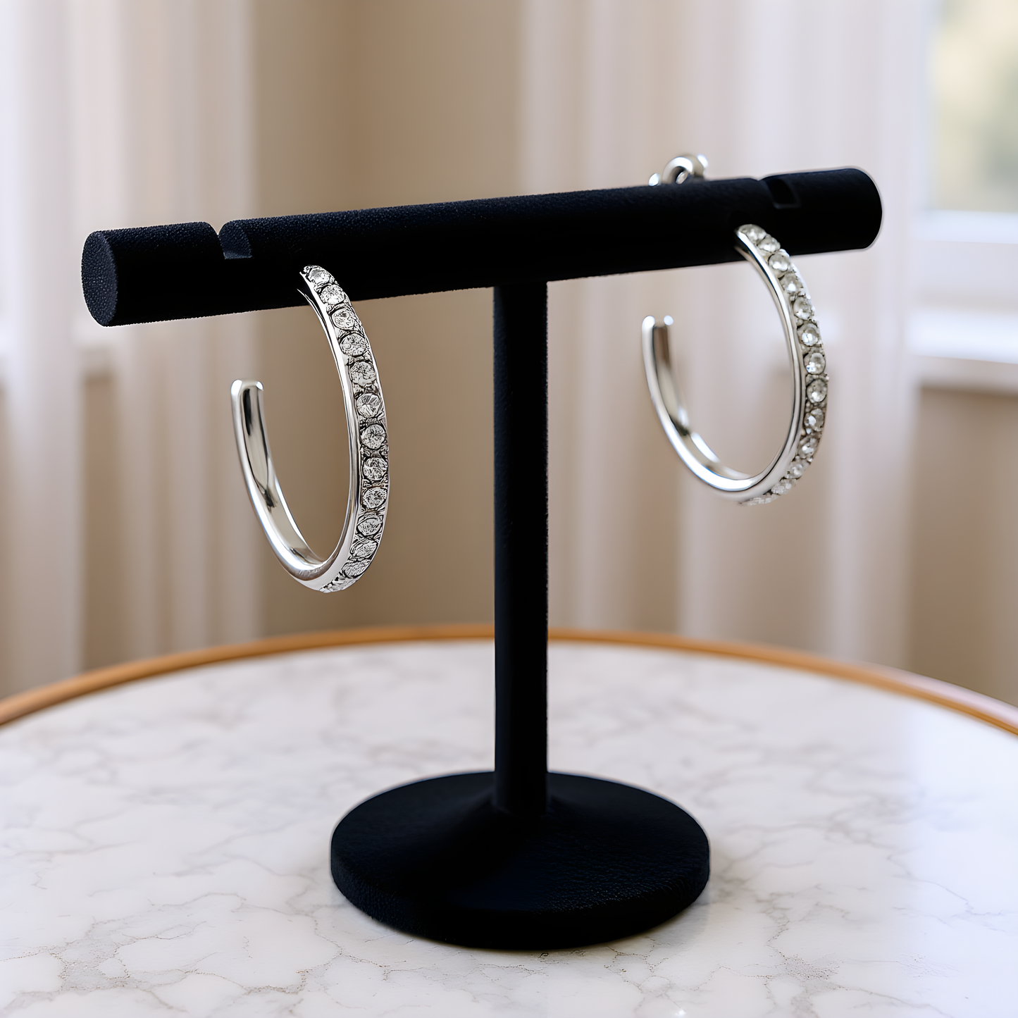 Silver hoop earrings on a black stand with a blurred background