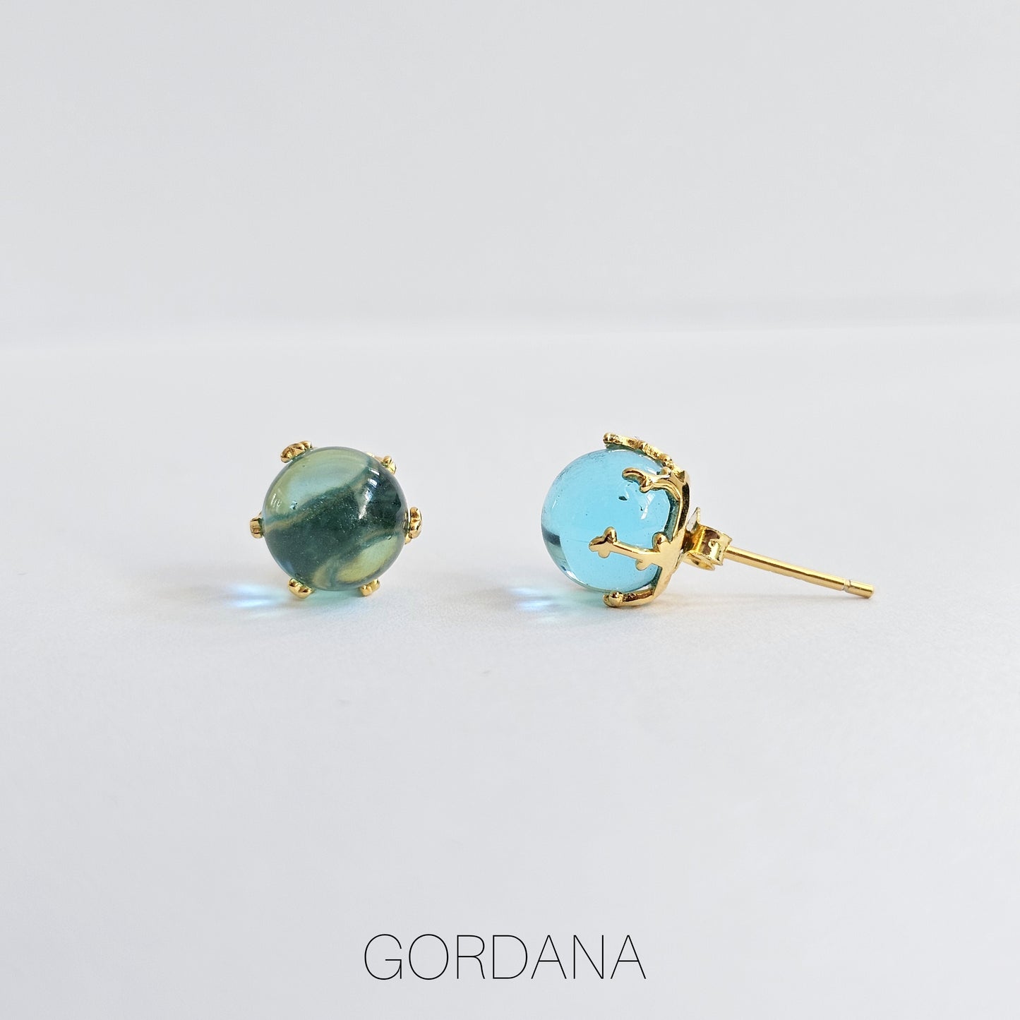 Elegant blue gemstone stud earrings in stainless steel with gold-tone prong setting, unisex fashion jewelry.